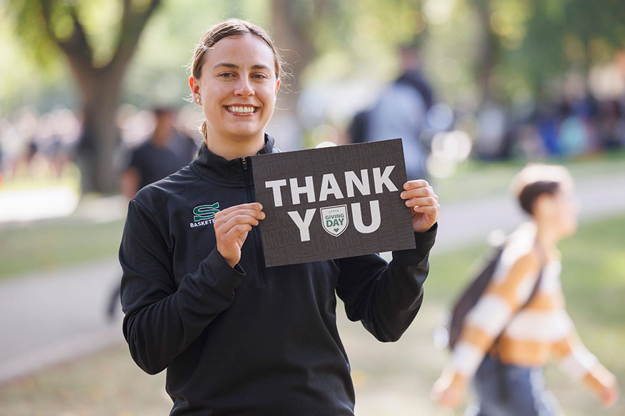 Libby Epoch, a University of Saskatchewan civil engineering student and former women's basketball Huskie athlete holds a thank you sign on the USask campus. (Photo: David Stobbe)